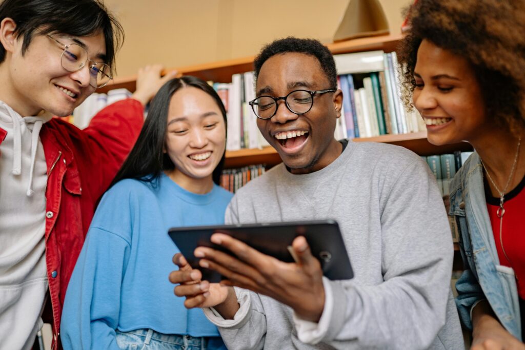 Students laughing at tablet in the classroom.